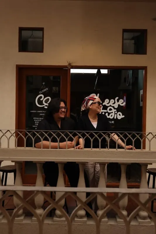 Addin and Umairah leaning on a balcony railing